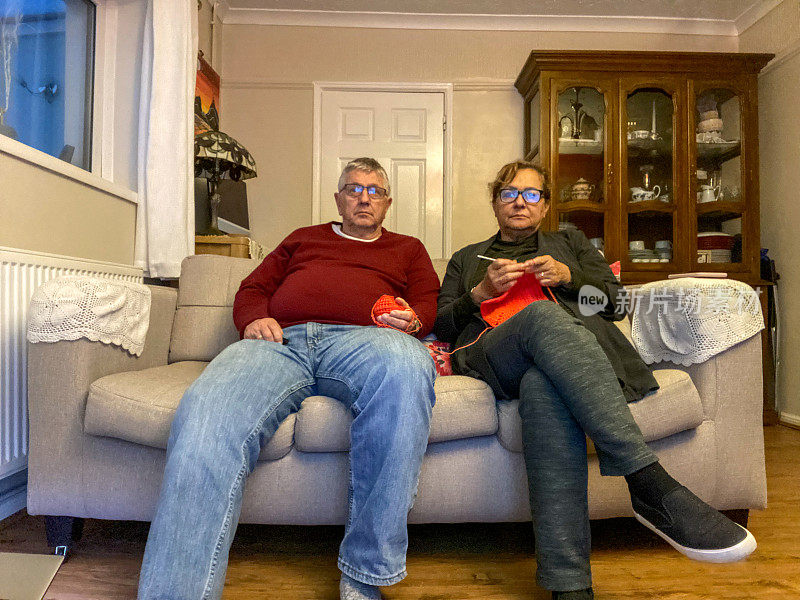 Senior mixed ethnicity couple watching TV on sofa